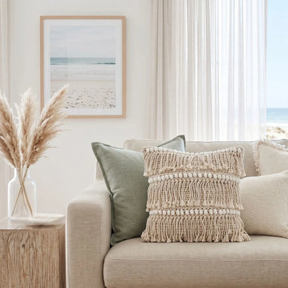 Living room with a beige sofa, decorative pillows, and a framed beach scene painting.