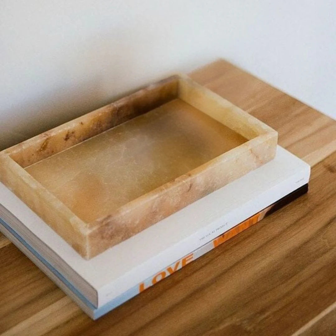 Rectangular onxy stone tray on a book with a wooden surface background