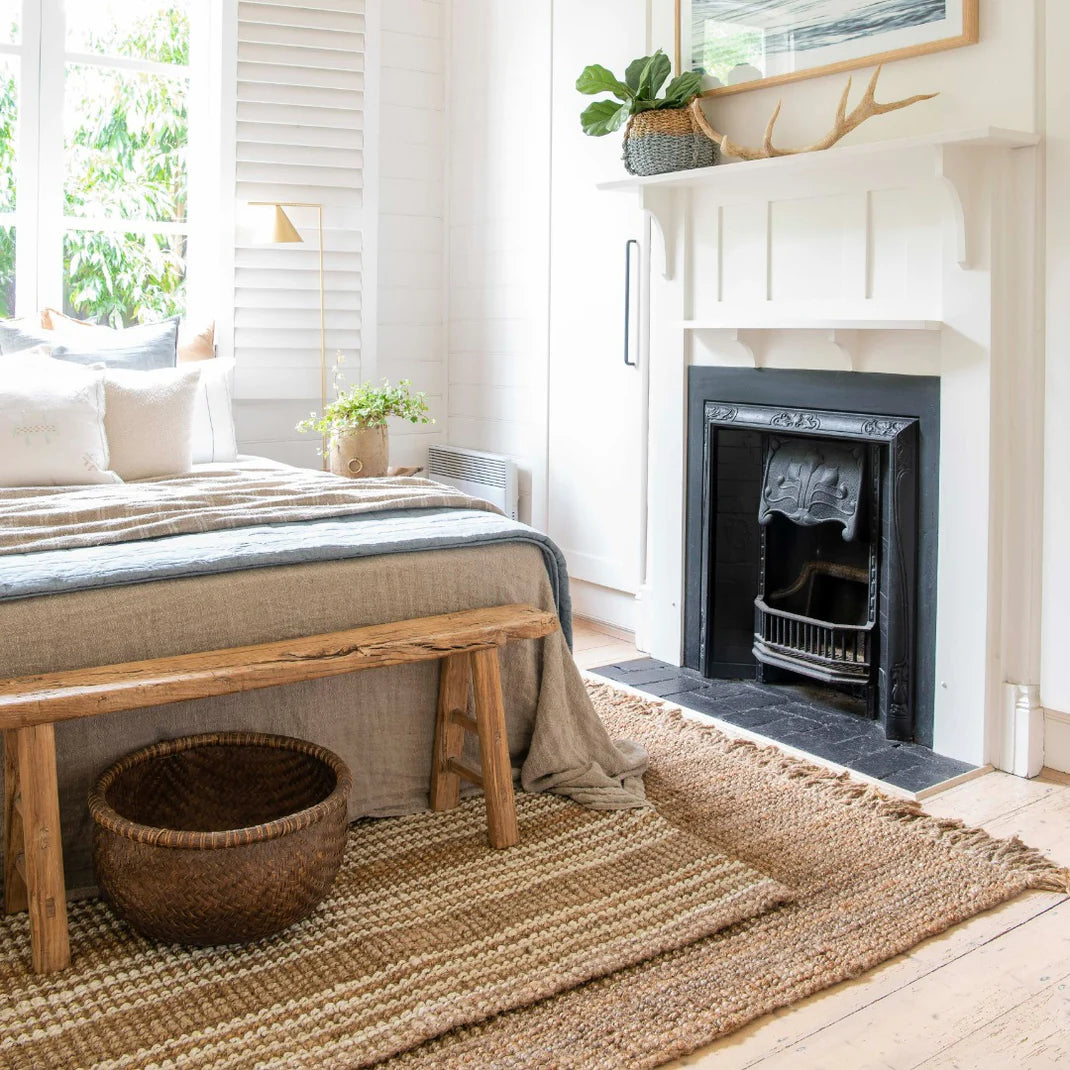 Cozy bedroom with a bed, wooden bench, and fireplace.