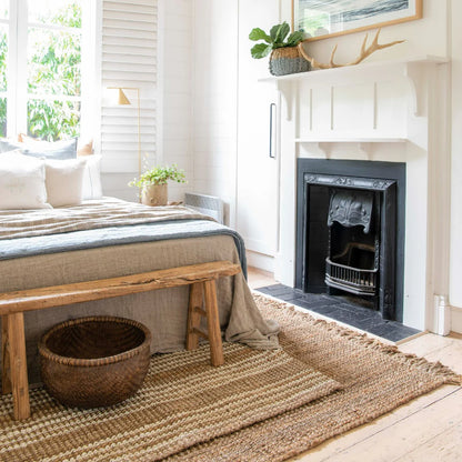 Cozy bedroom with a bed, wooden bench, and fireplace.