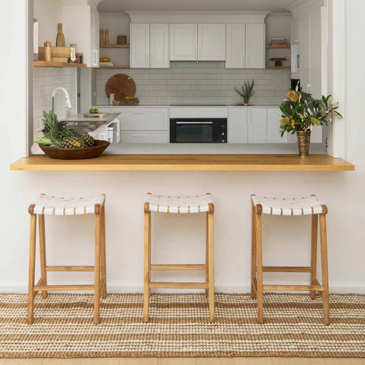 Modern kitchen with wooden bar counter and stools, featuring a neutral color palette.