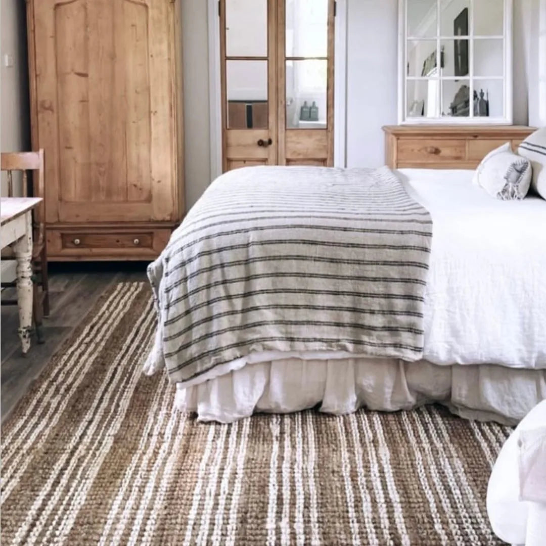 Bedroom with wooden wardrobe, dresser, and striped rug