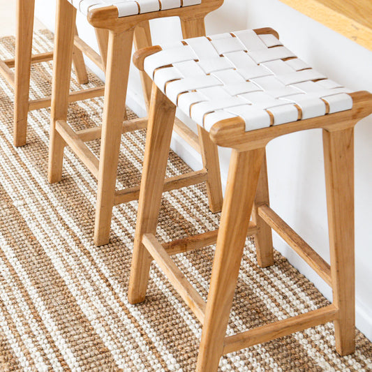 Wooden stools with woven seats on a striped rug