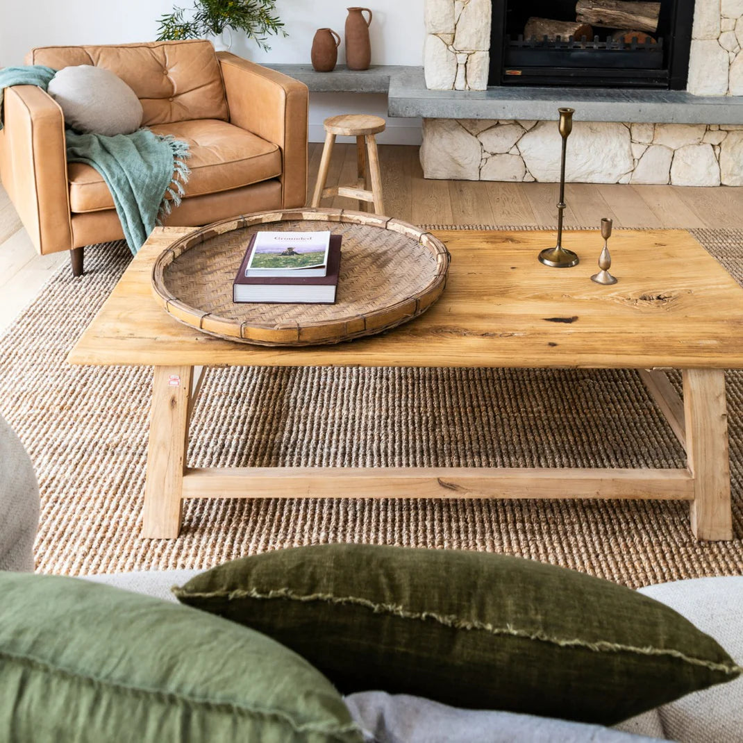 Living room with wooden coffee table, brown sofa, and stone fireplace.