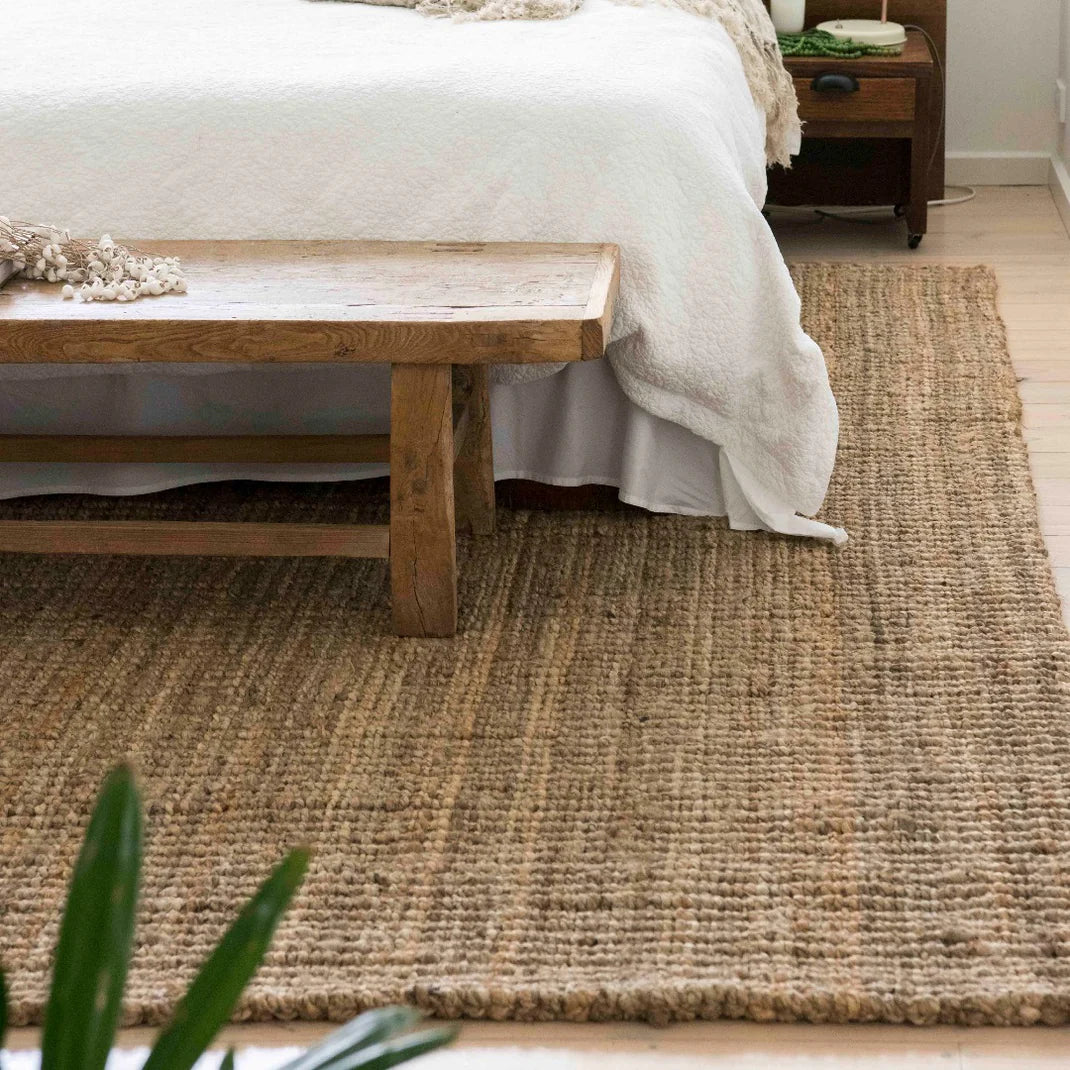 Bedroom with a wooden bench and textured rug