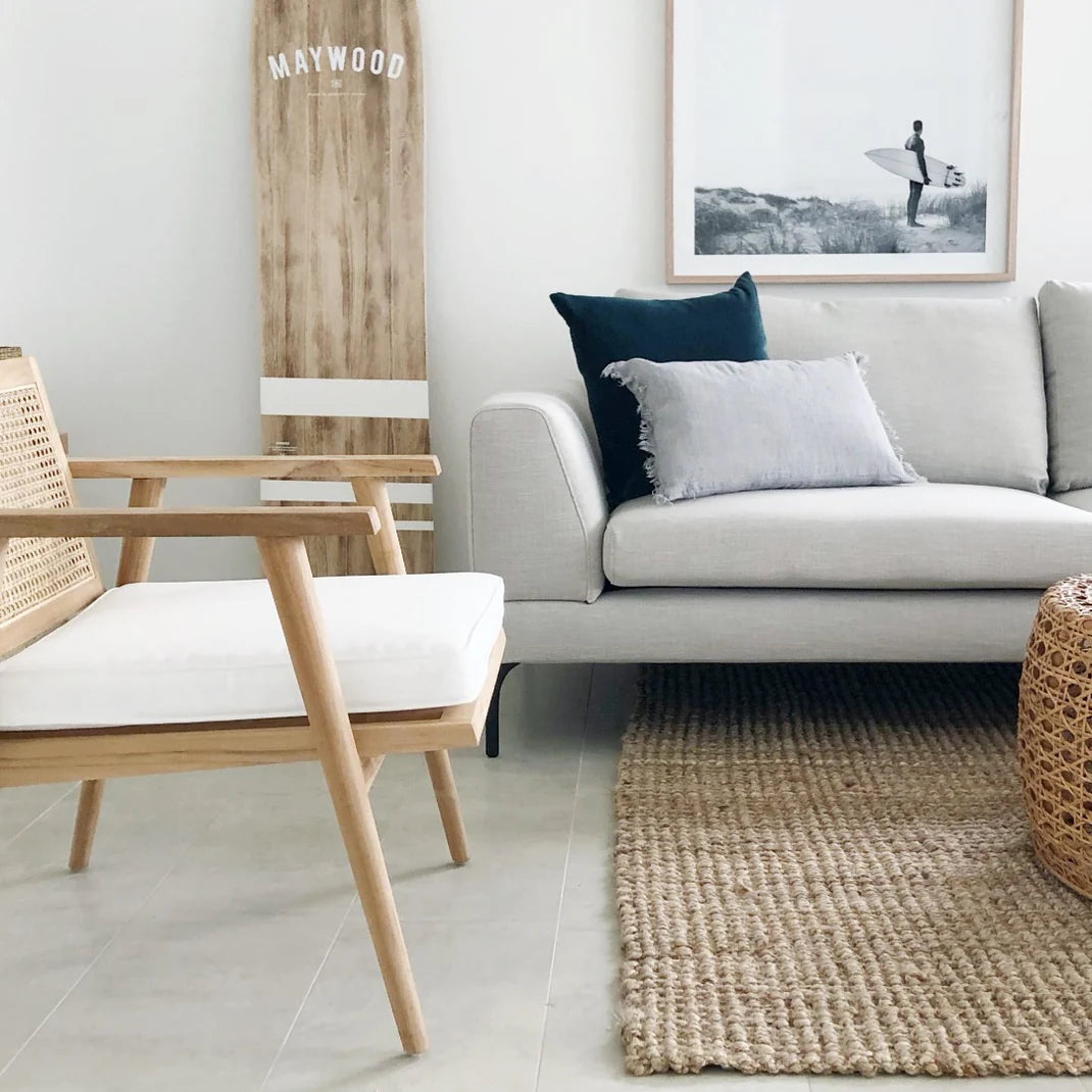Modern living room with a gray sofa, wooden chair, and framed artwork.