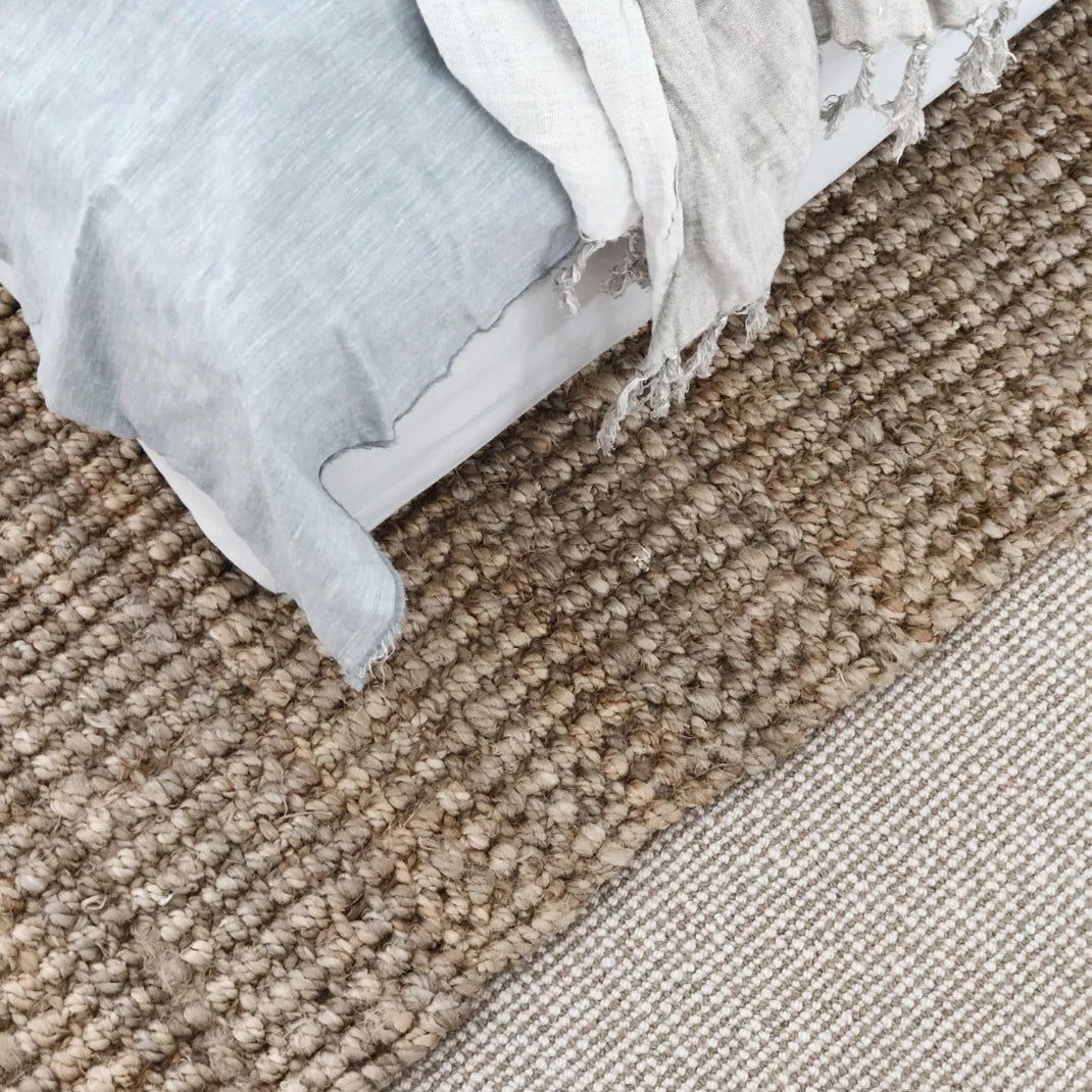 Close-up of textured beige carpet with a folded fabric item on top