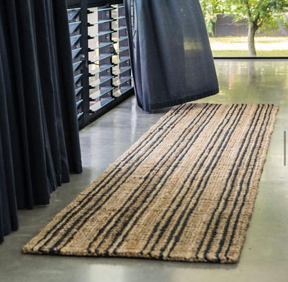 Long striped rug on a concrete floor with dark curtains in the background