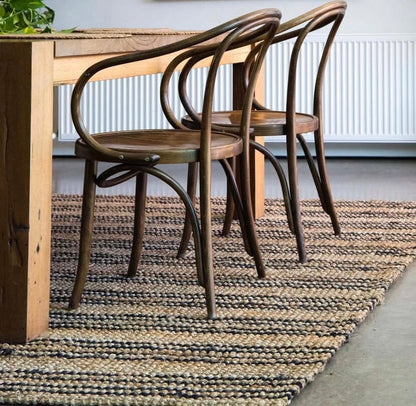 Wooden dining table with two chairs on a textured rug