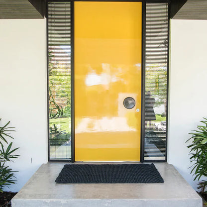 Modern house entrance with a yellow glass door and black doormat.