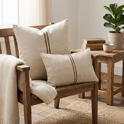Wooden armchair with patterned cushions and a small table with books and a plant in a cozy room.