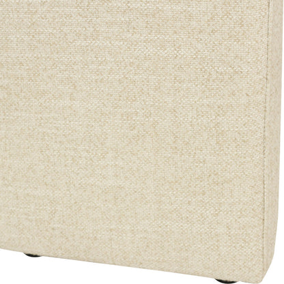 Close-up of a light beige textured fabric upholstered furniture corner, showing the weave and a small portion of a dark leg underneath on a white background.