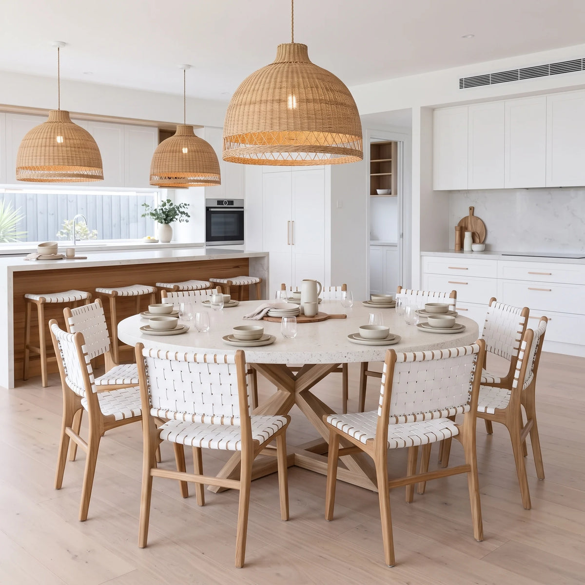 Modern kitchen and dining room featuring Sun Republic Otis woven leather and teak dining chairs and stools, rattan pendants and terrazzo stone dining table