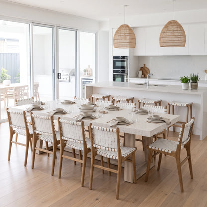 Modern kitchen and dining room featuring Sun Republic Otis woven leather and teak dining chairs and stools, rattan pendants and terrazzo stone dining table