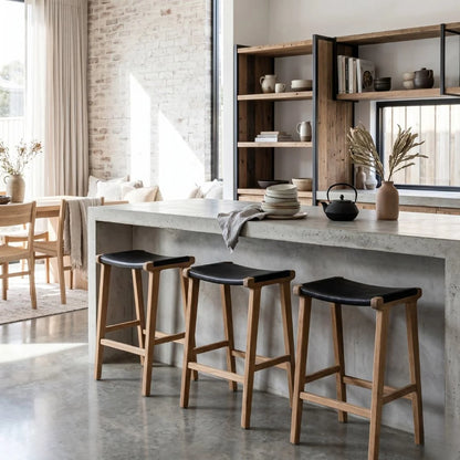 Sun Republic black leather and teak counter stools at an kitchen island bench in a modern home
