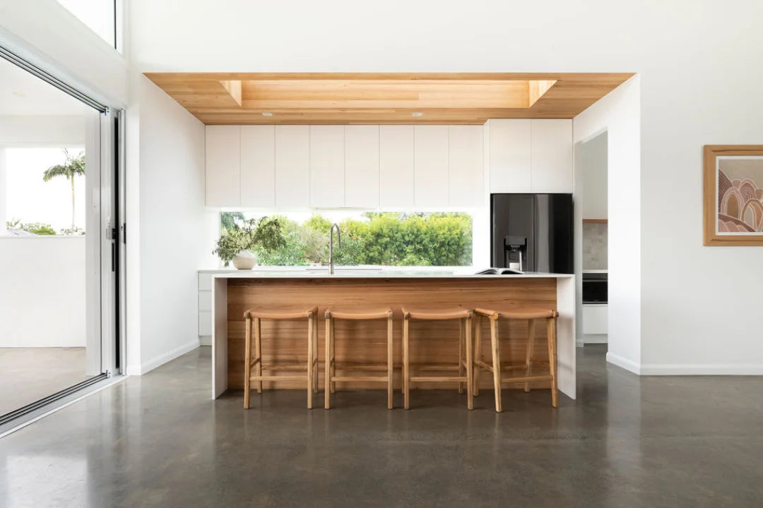 Natural Tan Leather and Teak stools in front of a kitchen counter with a window view.