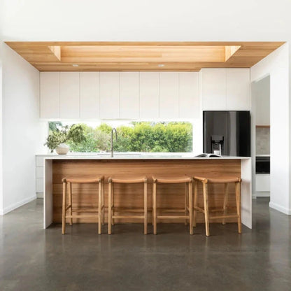 Natural Tan Leather and Teak stools in front of a kitchen counter with a window view.
