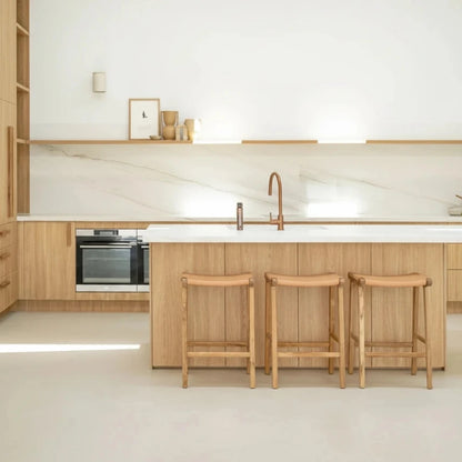 Modern kitchen with wooden cabinets, island, and stools.