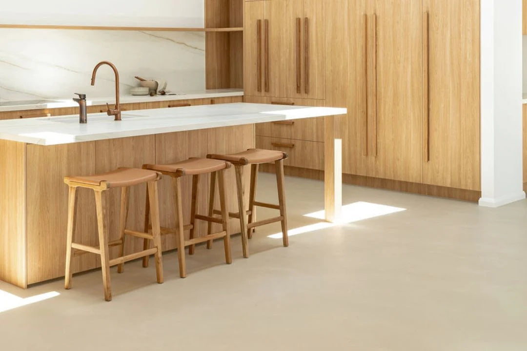 Modern kitchen with wooden cabinets, white countertops, and bar stools.