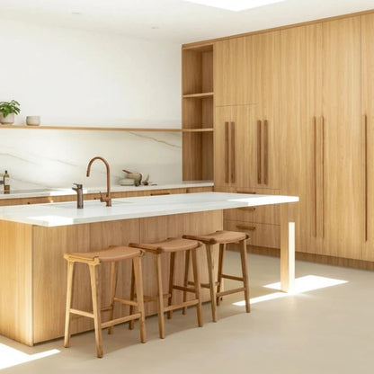 Modern kitchen with wooden cabinets, white countertops, and bar stools.