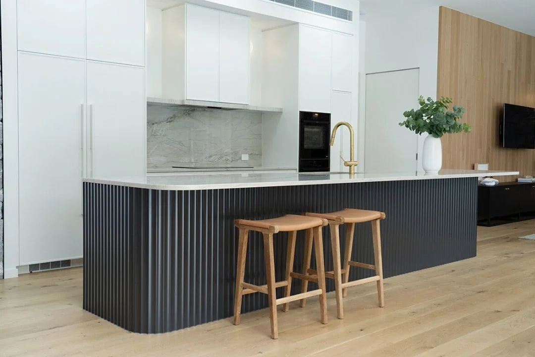 Modern kitchen with black island, wooden stools, and white countertops.