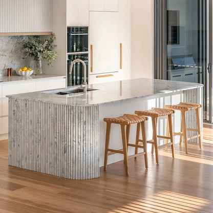 Sun Republic natural tan and teak woven leather counter stools in a modern kitchen.