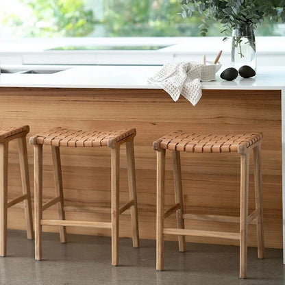 Wooden stools in front of a kitchen island with a sink and window in the background.