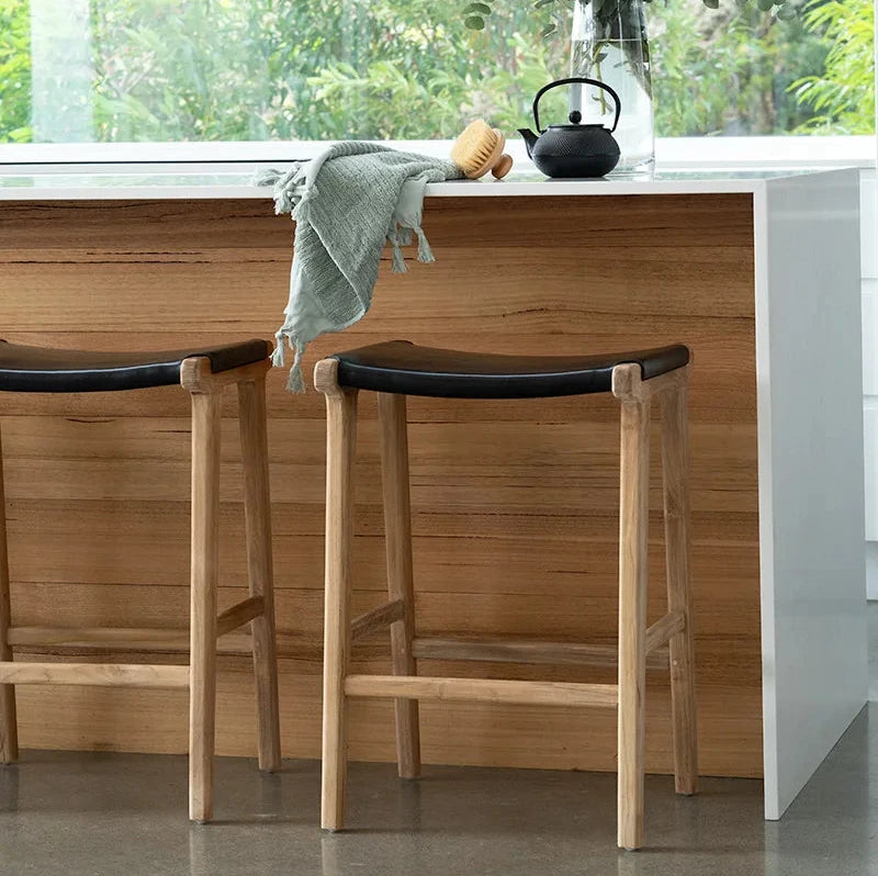 Modern kitchen with wooden stools, white countertop, and a window view of garden