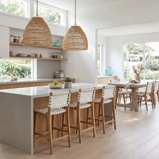 Modern kitchen with white island, wooden chairs, and wicker pendant lights.