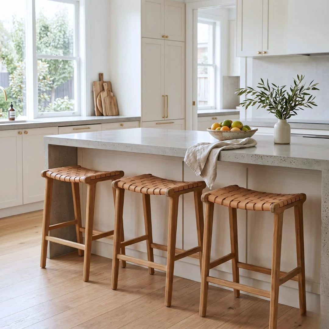 Sun Republic natural tan and teak woven leather counter stools in a modern kitchen.