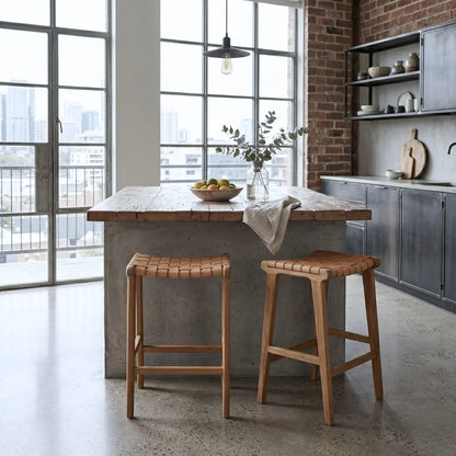 Sun Republic natural tan and teak woven leather counter stools in a modern industrial apartment kitchen.