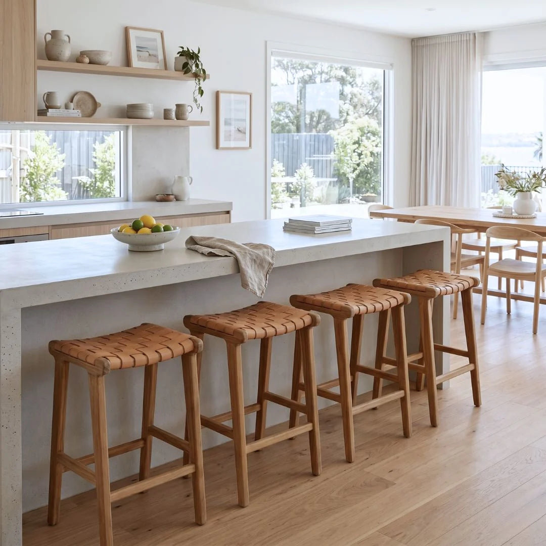 Sun Republic natural tan and teak woven leather counter stools in a modern kitchen.