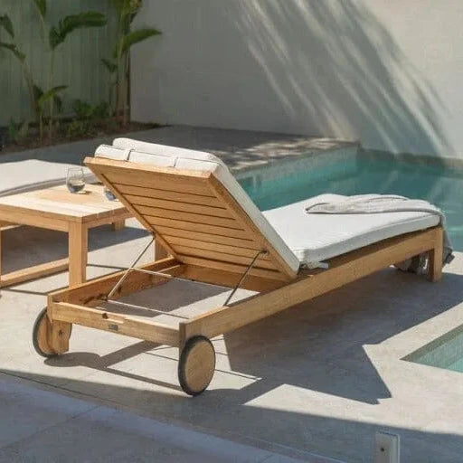 Wooden lounge chair with white cushions by a poolside