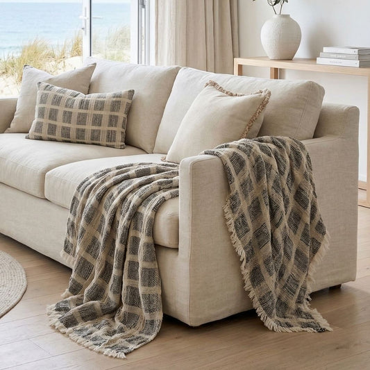 Beige sofa with plaid throw blanket in a bright living room