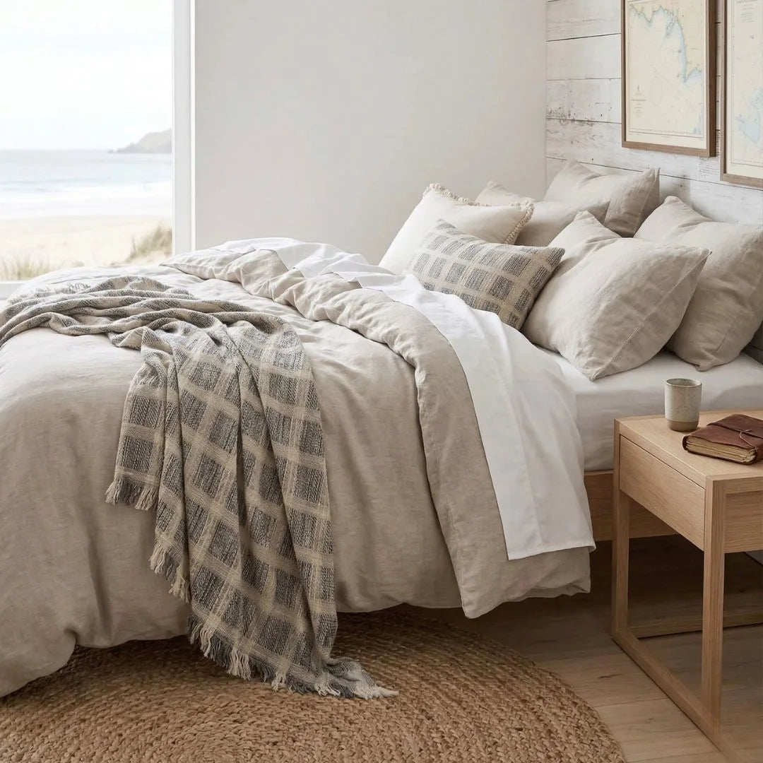 Neatly made bed with plaid blanket and pillows in a bedroom setting.