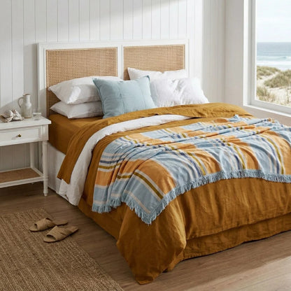 Bedroom with a bed featuring a striped comforter and wicker headboard.