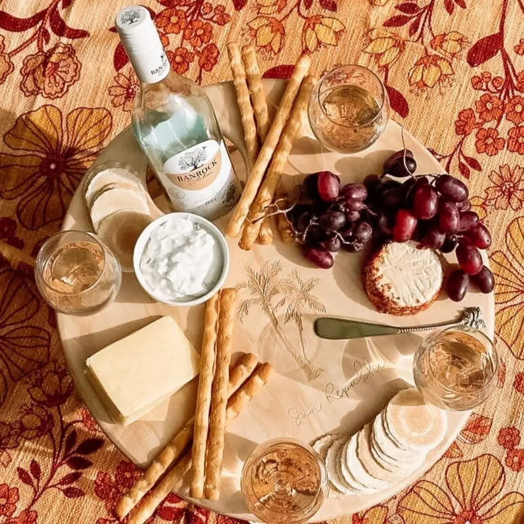 Platter with wine, cheese, grapes, and bread on a patterned tablecloth