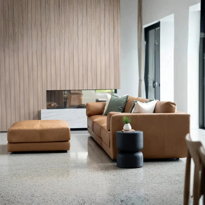 Modern living room with brown sofa, ottoman, and decorative items.