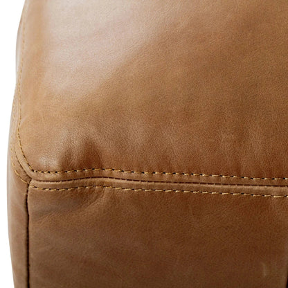 Close-up of a brown leather ottoman with visible stitching.