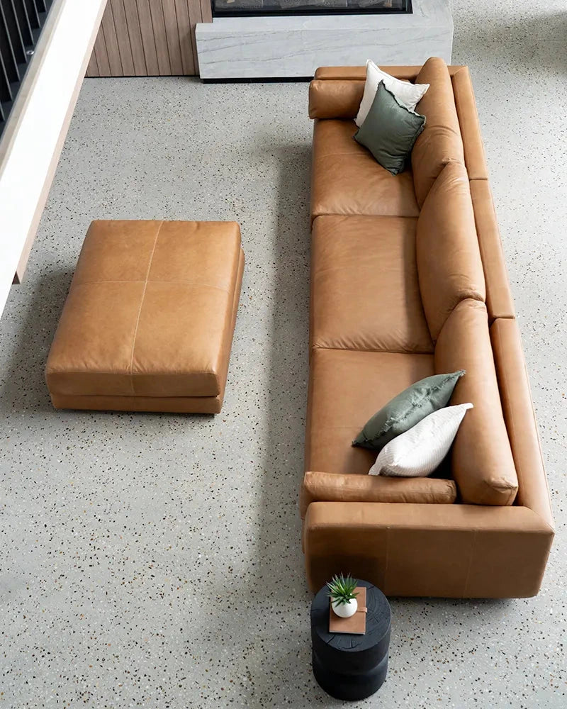 Brown leather sofa with cushions in a modern living room setting.