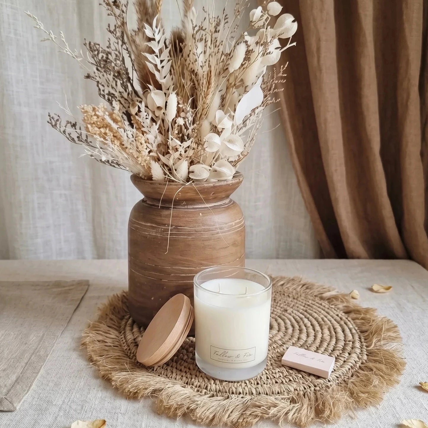 Candle and dried flowers on a textured surface with neutral colors