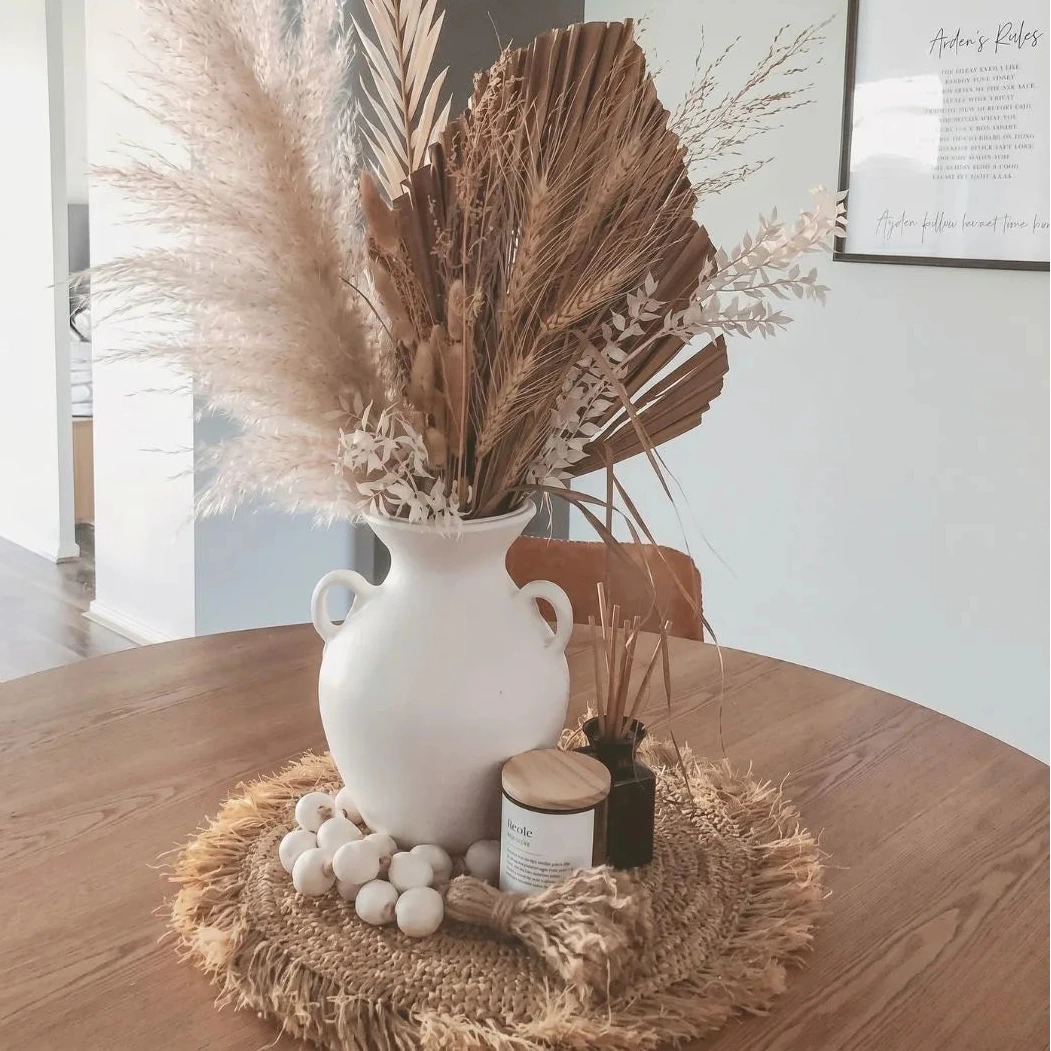 White vase with dried plants on a wooden table