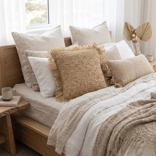 Cozy bedroom with a bed featuring textured pillows and blankets, next to a wooden nightstand.