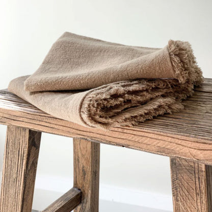 Beige blanket on a wooden stool with a white background
