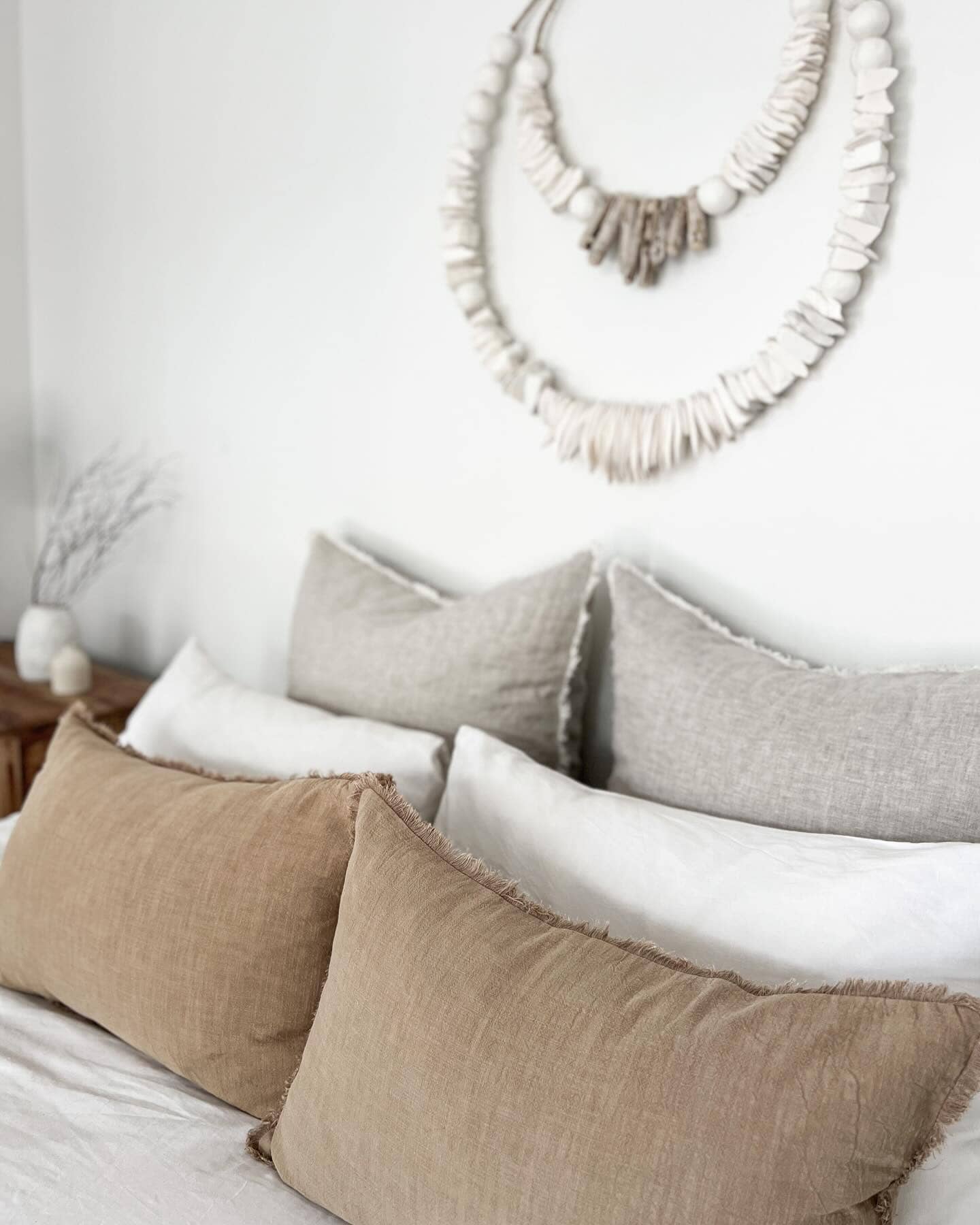 Neatly arranged pillows on a bed with decorative wall art in the background.