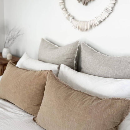 Neatly arranged pillows on a bed with decorative wall art in the background.