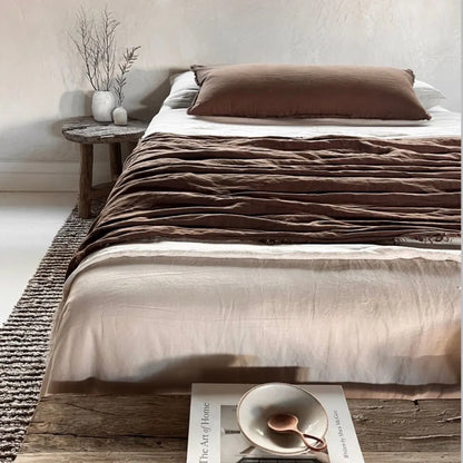 Bed with brown bedding and a wooden side table in a bedroom setting