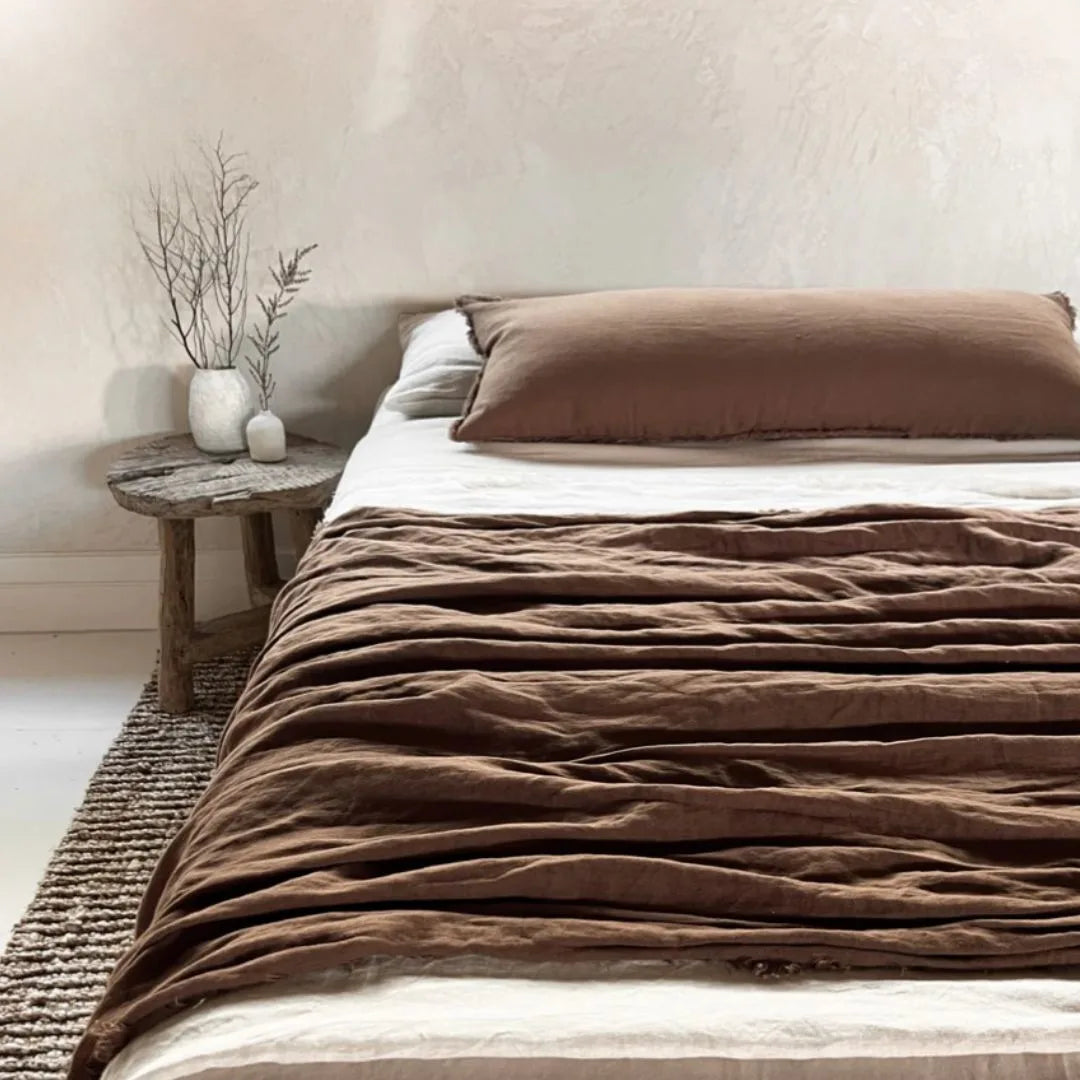 Bed with brown bedding and pillows in a bedroom setting.