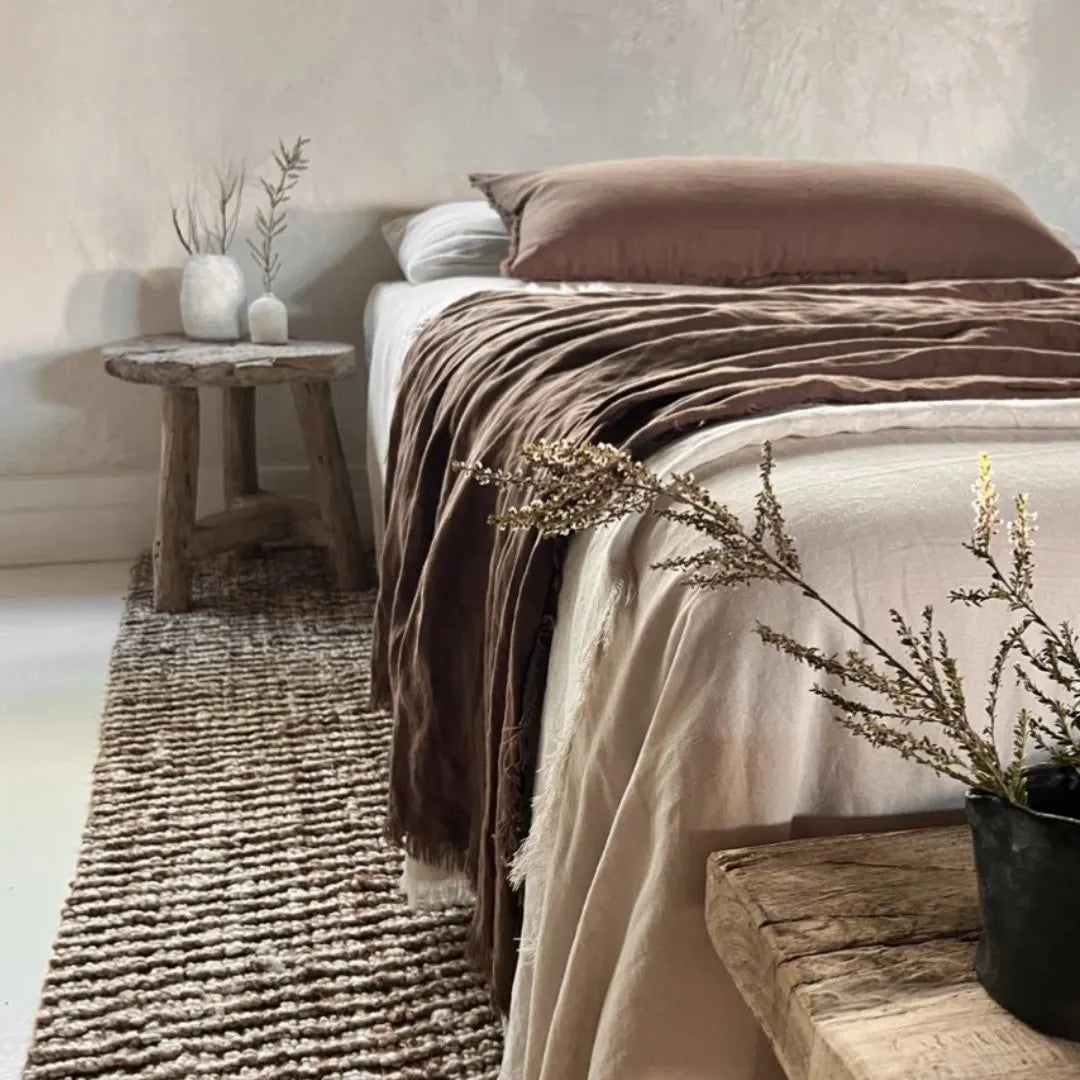 Cozy bedroom with a bed, wooden bench, and decorative plants.