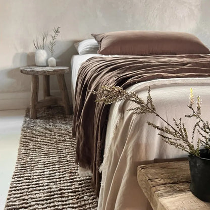 Cozy bedroom with a bed, wooden bench, and decorative plants.